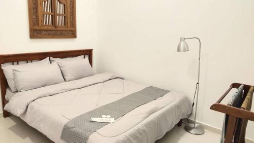 关丹Orchid Guesthouse Kuantan的卧室配有一张带灯的白色大床