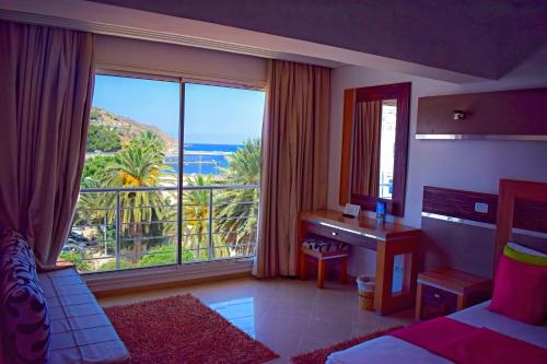 塔巴卡普雷斯蒂奇塔巴卡码头酒店的一间卧室配有一张床、一张书桌和一个大窗户