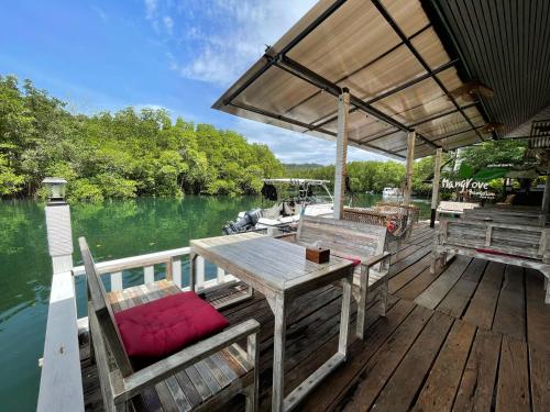 库德岛Mangrove bungalow & restaurant的船上的木制甲板上配有桌椅