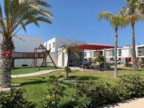 恩塞纳达港#CasaMare - Privada a una cuadra del mar con AC的一个带棕榈树游乐场和秋千的公园