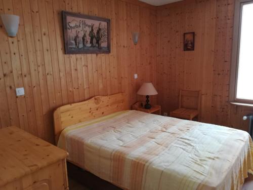 蒂涅Appartement Tignes, 2 pièces, 5 personnes - FR-1-449-137的卧室配有一张床铺,位于带木墙的房间内