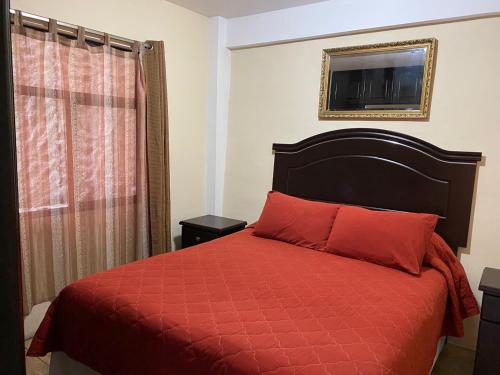 克萨尔特南戈Apartamento #2 Portal de Occidente的一间卧室配有一张带红色棉被的床和窗户。