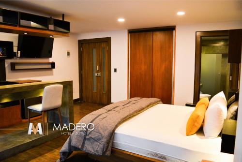 拉巴斯Madero Hotel & Suites的一间带一张床和一张书桌的卧室和一间厨房