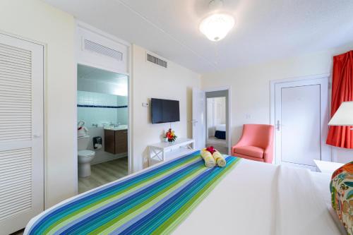 辛普森湾拉维斯塔海滩度假酒店的卧室配有白色的床和色彩缤纷的毯子