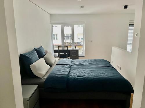 慕尼黑Modern Apartment in the center of Munich的一间卧室配有一张带蓝色床单的床和一扇窗户。
