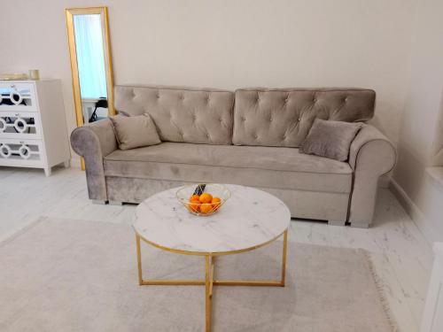 海乌姆Apartament Glamour Chełm的客厅配有沙发和桌子上的一碗橙子
