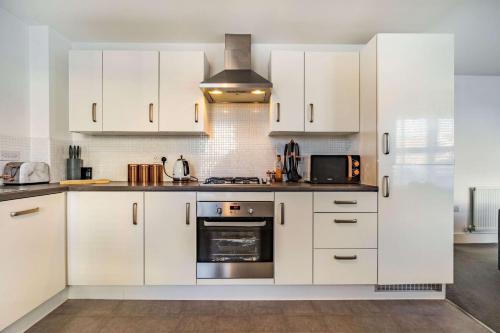 泰恩河畔纽卡斯尔Anox serviced apartment的厨房配有白色橱柜和炉灶烤箱。