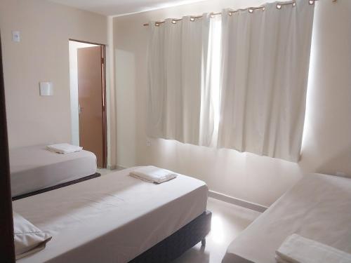 坎普斯戈伊塔卡济斯Hotel hawaii的白色的客房设有两张床和窗户。