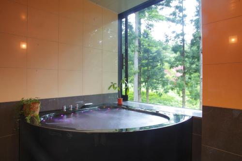 白马村HakubaGoryu Pension&LogCottage Arumu的一间带大浴缸及窗户的浴室