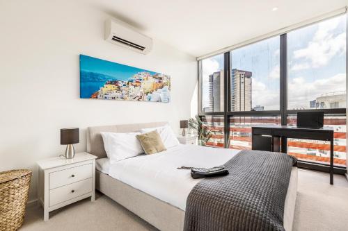 墨尔本KULA Docklands的一间卧室配有一张床、一张书桌和一个窗户。