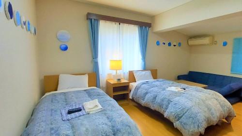 MitoyoLe Port Awashima的一间卧室配有两张床和蓝色的沙发