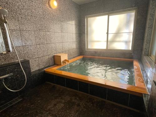 茅野小水鸟酒店的带浴缸和窗户的浴室
