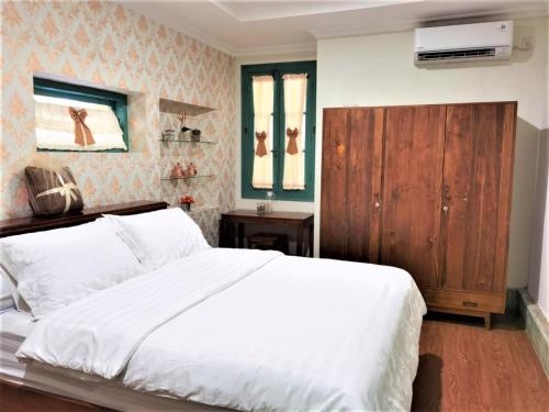 梭罗Ndalem Kinasih Homestay Syariah的卧室配有白色的床和木制橱柜。