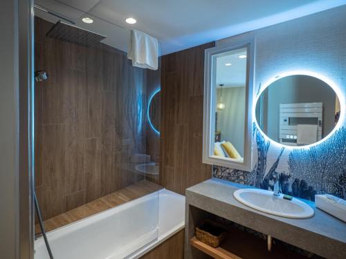格鲁瓦HOTEL LA MARINE的带浴缸、水槽和镜子的浴室