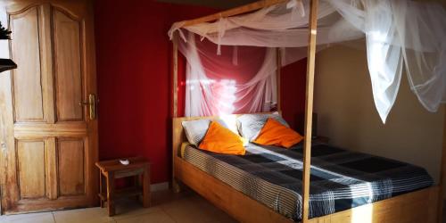 PoponguineChez medzo et patou的一间卧室配有带橙色枕头的天蓬床