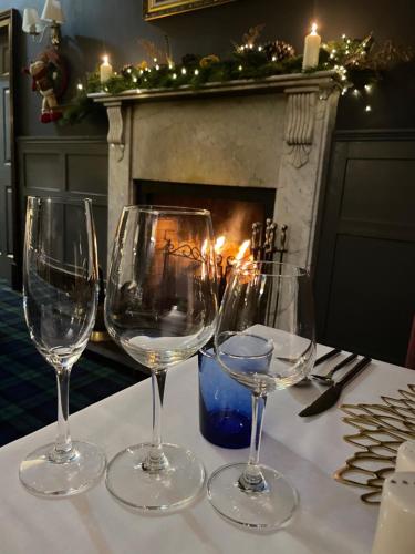 福耶斯Craigdarroch Hotel的四杯酒杯坐在壁炉旁的桌子上