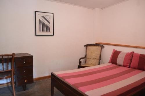 哈普特莱The Lodge at Galapitiyaya Estate的一间卧室配有一张床、梳妆台和椅子