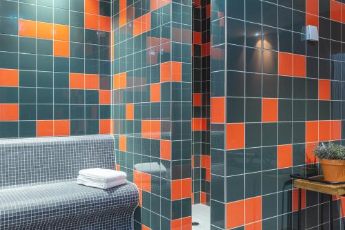 波茨坦the niu Amity的浴室的墙壁上铺有橙色和蓝色的瓷砖。