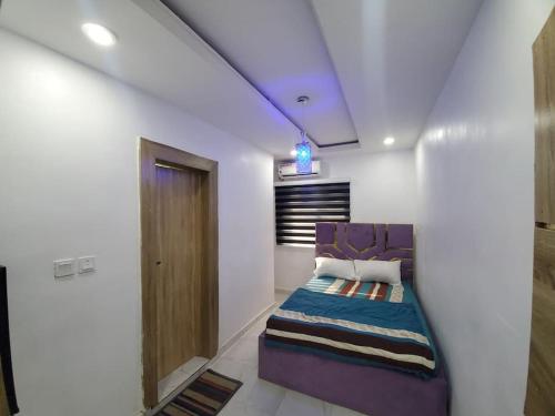 拉各斯Dinero Rose-2 Bedroom Apartment的白色客房内的一间卧室配有紫色沙发