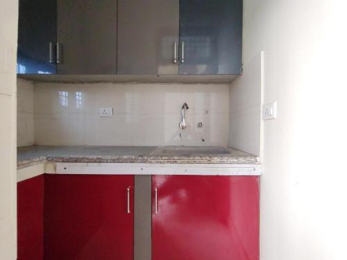 阿里格尔Nisha Homestay的一个带水槽和红色橱柜的厨房