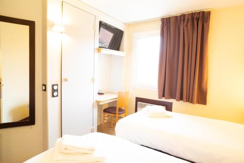 巴约讷Hôtel Les Genêts Bayonne的酒店客房,设有两张床和镜子