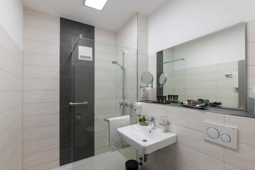 博登斯边的拉多夫采尔斯塔德花园酒店的白色的浴室设有水槽和淋浴。