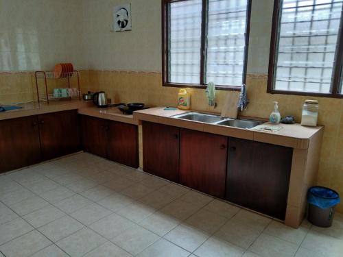 怡保QQ Homestay的厨房配有木制橱柜、水槽和2扇窗户。