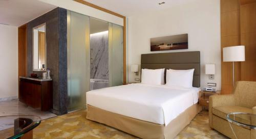 浦那Hyatt Regency Pune Hotel & Residences的卧室配有一张白色大床和一把椅子