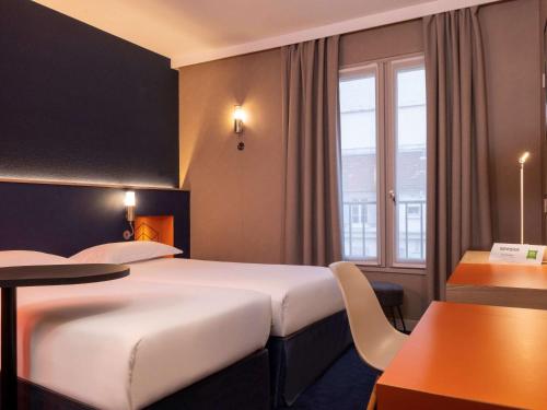 皇后堡ibis Styles Bourg La Reine的酒店客房设有两张床和一张桌子。