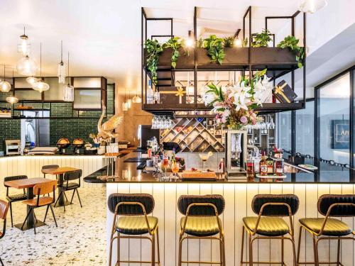 新加坡Mercure Singapore Tyrwhitt的餐厅设有酒吧,配有桌椅