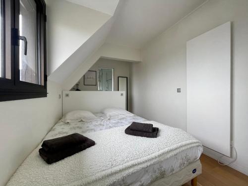 多维尔Deauville Harmonie - Tout à pied, Balcon & Modernité的卧室配有白色床和2条黑色毛巾