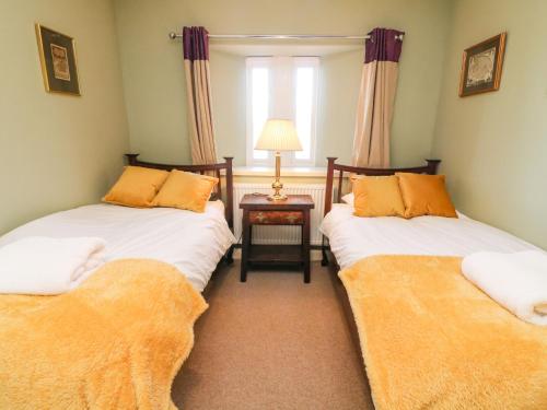 康福斯Langthwaite Cottage的带窗户的客房内设有两张单人床。