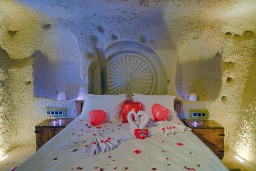内夫谢希尔Babili Cappadocia Cave Hotel的上面有红色心的床铺