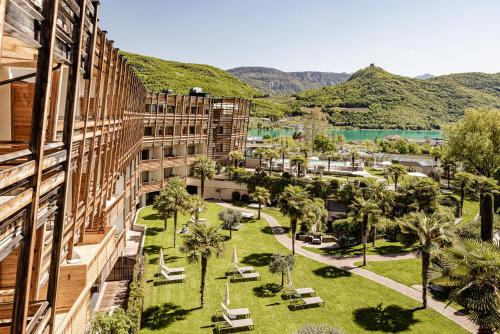 卡尔达罗Lake Spa Hotel SEELEITEN的享有建筑和棕榈树公园的景色