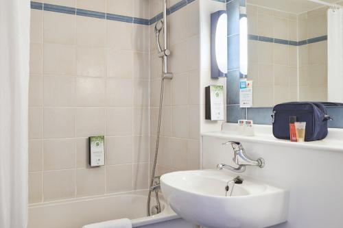 埃皮纳勒Kyriad Direct Epinal的浴室配有水槽、淋浴和浴缸。
