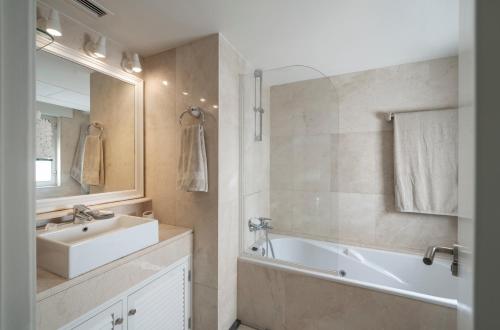 索托格兰德Houmi Sotogrande的一间带水槽、浴缸和镜子的浴室