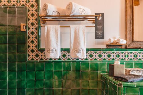帕茨库卡罗El Edén Hotel Boutique的绿色瓷砖浴室设有两面镜子和毛巾