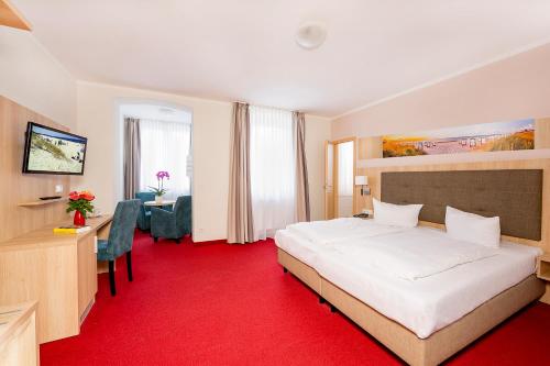 塞巴特阿尔贝克Hotel Garni Sonne的酒店客房配有一张白色大床和红地毯
