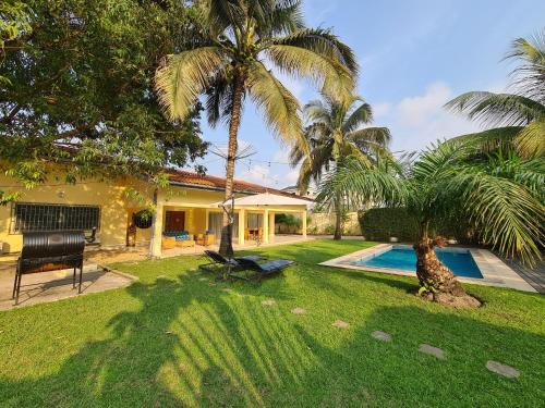 黑角Sompteuse villa avec piscine à 5 min de la plage的一座带游泳池和棕榈树的庭院的房子