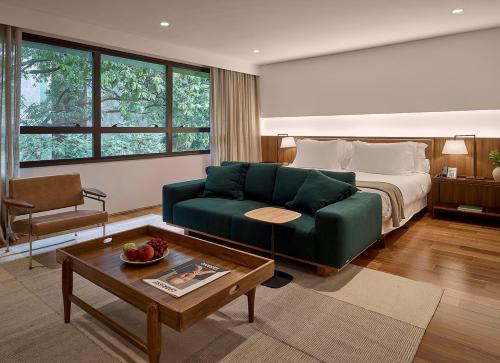 贝洛奥里藏特Hotel Fasano Belo Horizonte的客厅配有绿色沙发和床。