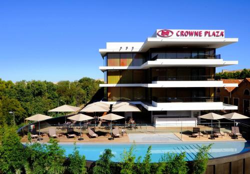 蒙彼利埃皇冠假日佩里尔峰库尔姆酒店的一座带游泳池、桌子和遮阳伞的建筑