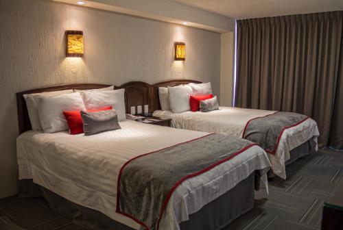 莱昂Ramada Plaza by Wyndham Leon的酒店客房 - 带两张带红色枕头的床