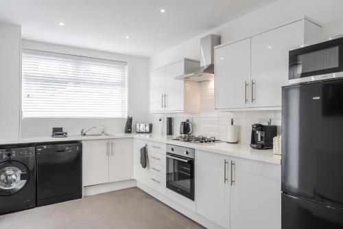 利物浦Denebank Lodge - Anfield Apartments的厨房配有白色橱柜和黑色洗碗机