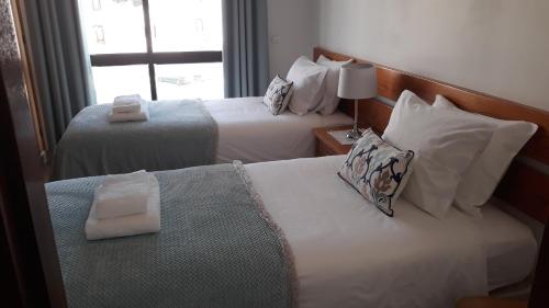 塞勒玛Salema Beach Apartment的酒店客房设有两张床和窗户。