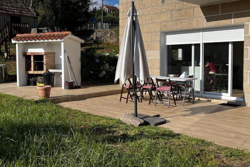 庞特维德拉Agradable casa rural entre Pontevedra y Arcade的庭院配有遮阳伞和桌椅。