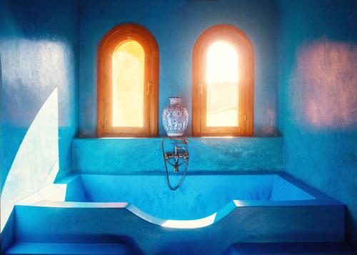 马拉喀什Riad Roxanne的蓝色的浴室设有浴缸和2扇窗户