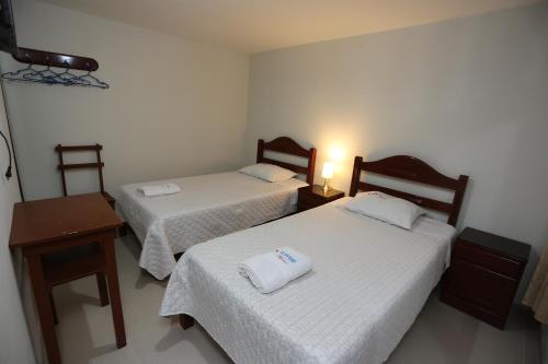 卡哈马卡Witobi Hostal的客房设有两张床、一张桌子和一盏灯。