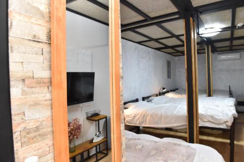 小樽Motel inn Minami Otaru / Vacation STAY 50444的一间卧室设有两张床、一台电视和砖墙