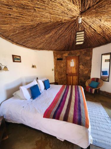 圣佩德罗·德·阿塔卡马Masairi的一间卧室设有一张带茅草天花板的大床