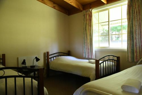 Neerim South涅尔姆乡村小屋度假酒店的一间卧室设有两张单人床和一个窗户。